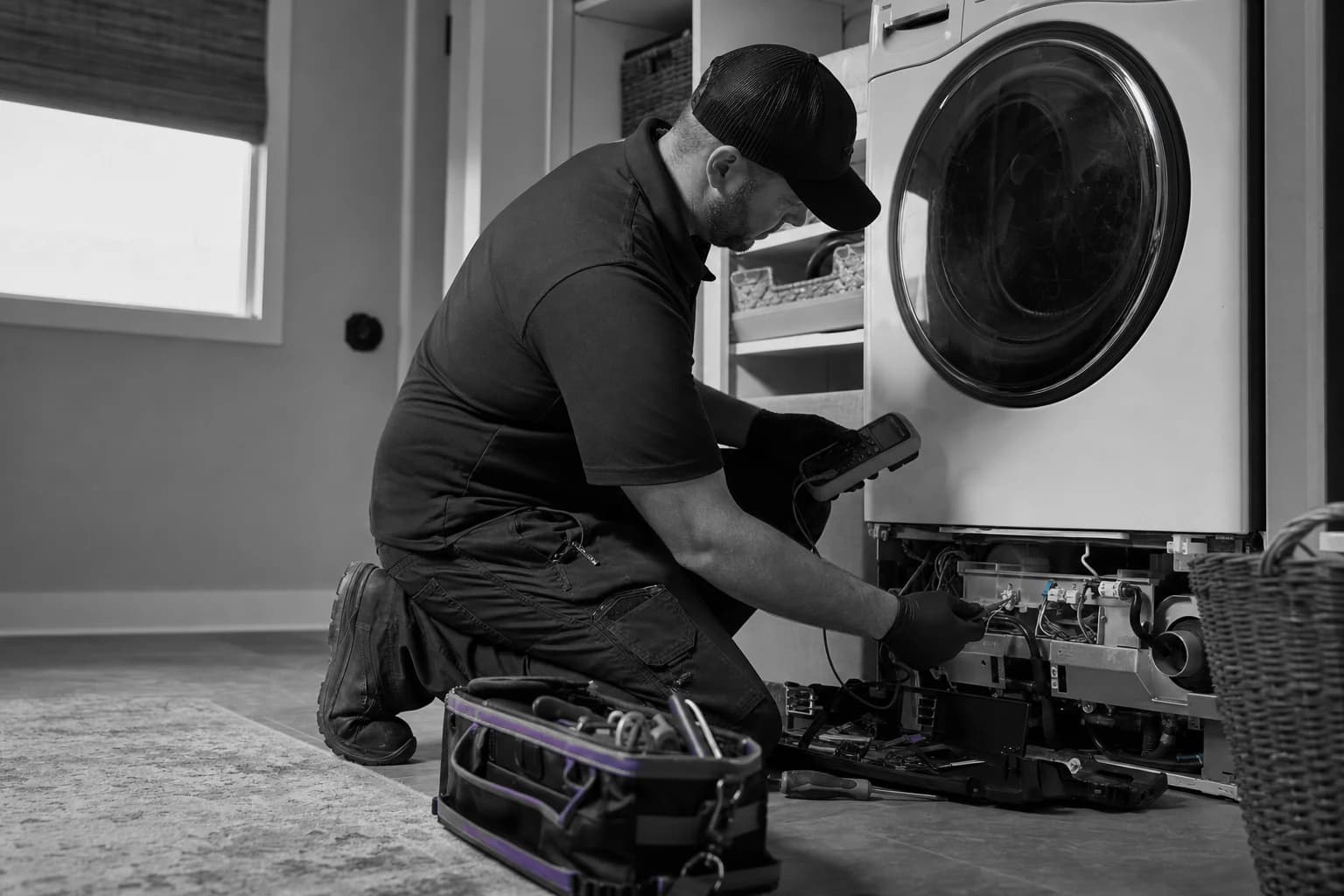 Appliance technician testing an open washing machine in a customer home